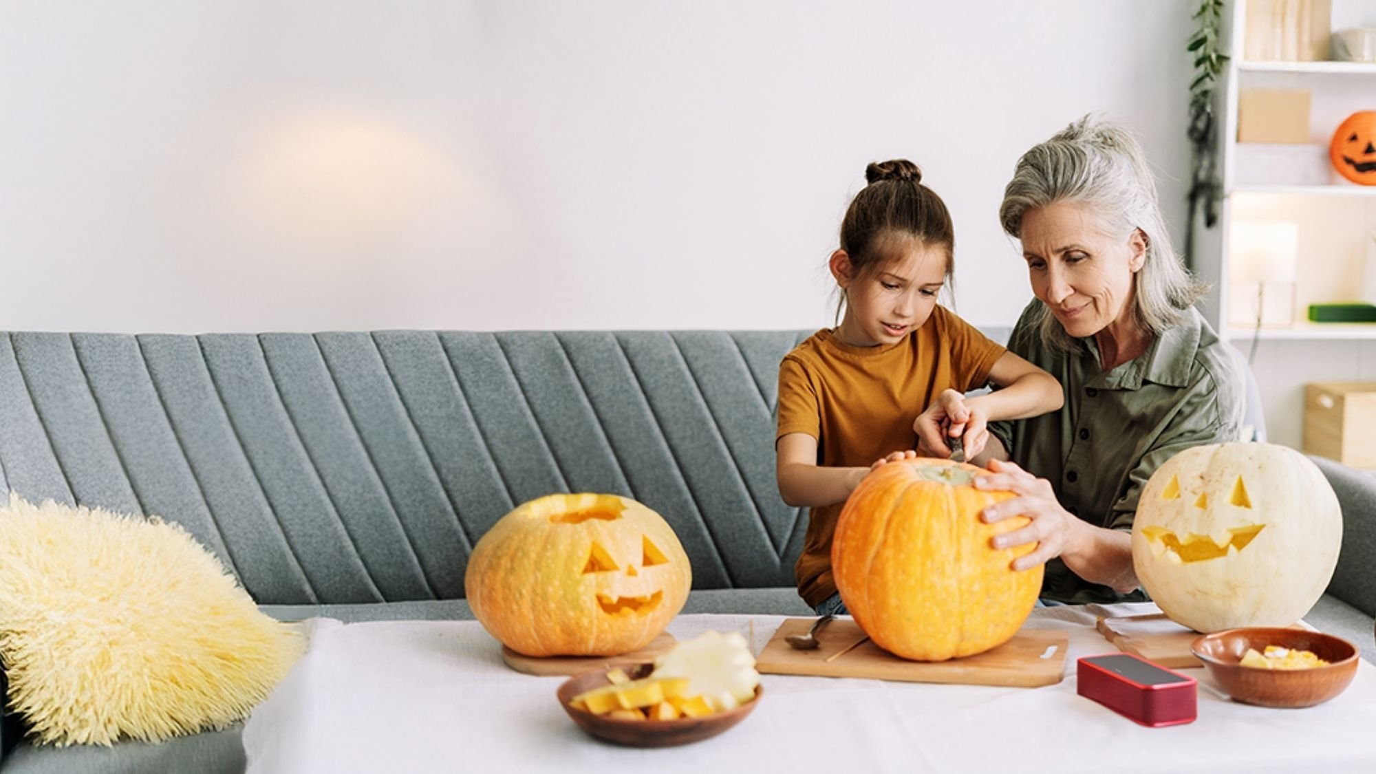 Child and grandmother carving pumpkins